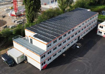 Drohnenaufnahme einer großflächigen Photovoltaikanlage auf modularen Bürocontainern – nachhaltige Solartechnik zur umweltfreundlichen Stromversorgung auf einer modernen Baustelle.