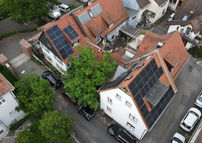 Luftaufnahme eines Wohngebiets mit mehreren Photovoltaikanlagen in Offenbach – moderne Solarmodule auf Ziegeldächern für nachhaltige Solarenergie.